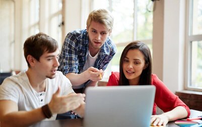 A group of people looking at a laptop