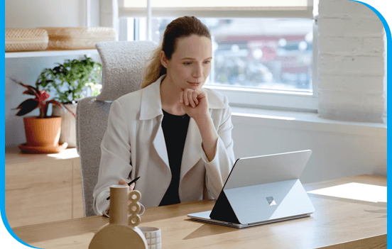A girl sitting at a table looking at a laptop