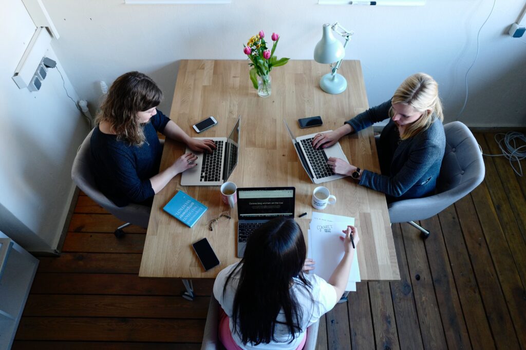 A group of women sitting at a table with laptops.